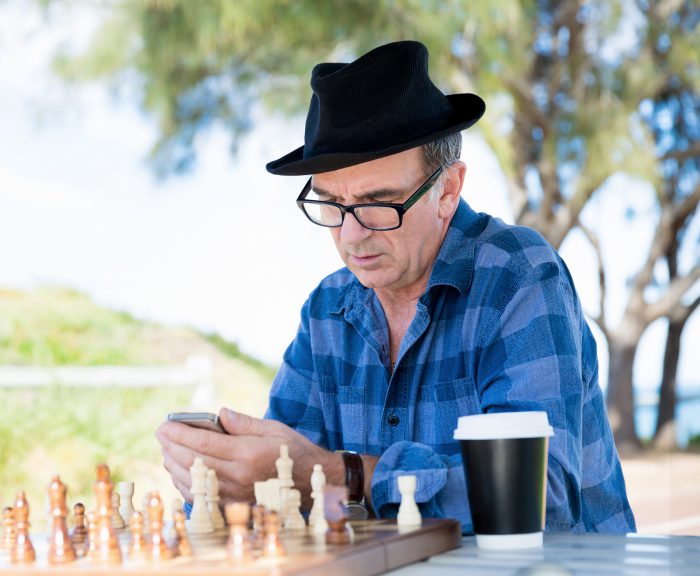 Man with glasses using smartphone and drinking a coffee in outdoor public space