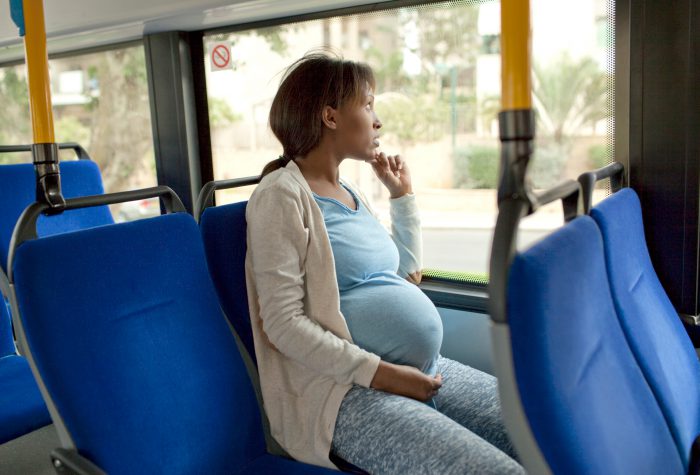 Pregnant lady sitting on bus, looking out of window