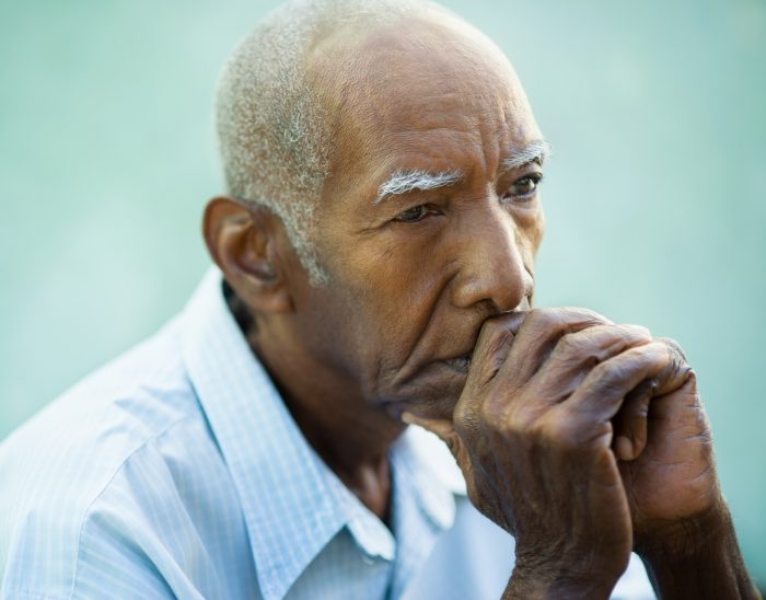 Male pensioner sat with thoughtful expression